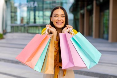 Bir sürü renkli alışveriş torbalarıyla poz veren mutlu kadın portresi indirimli satışlardan keyif alıyor. Ticaret ve başarılı alışveriş zamanı