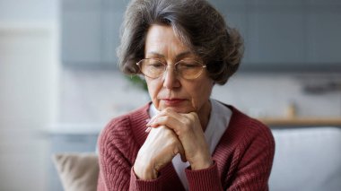 Düşünceli bunalımlı son sınıf öğrencisi kadın evde tek başına oturuyor, aşağıya bakıyor ve sorunları düşünüyor.