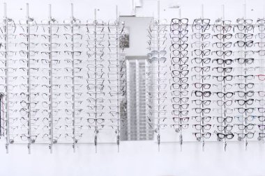 Optisyenler alışveriş yapar. Birkaç sıra halinde duvarda diopterli bir sürü farklı bardak var.