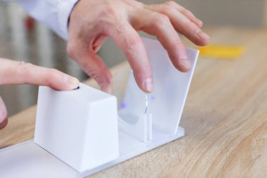 Optik klinikte test ettikten sonra fotokromik gözlük merceği tutan profesyonel optometrist, seçici odak, yakın çekim