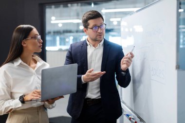 Yeni proje planlayan ve geliştiren iş arkadaşları, beyaz tahta önünde başarılı iş stratejisi planını tartıştılar