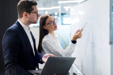 İşbirliği ve takım çalışması konsepti. Yeni projede birlikte çalışan iş adamları, tahtanın yanında durmak, geliri tahmin etmek, riskleri analiz etmek, hedefler belirlemek.
