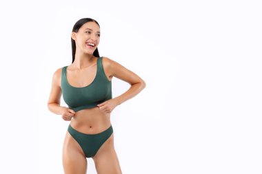 Yeşil iç çamaşırlı, formda bir kadın beyaz stüdyo arka planında izole bir şekilde poz veriyor. Vücut şeklini gösteriyor.