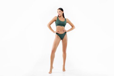 Beyaz stüdyo arka planında izole edilmiş, mükemmel vücut şekli olan yeşil iç çamaşırlı genç bir kadın.