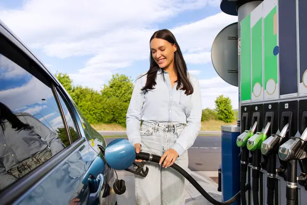 Otomobil yakıt ikmali teklifi. Gülümseyen kadın sürücü modern benzin istasyonunda otomobili biyo yakıtla dolduruyor. Çevre dostu ve uygun araba bakımı
