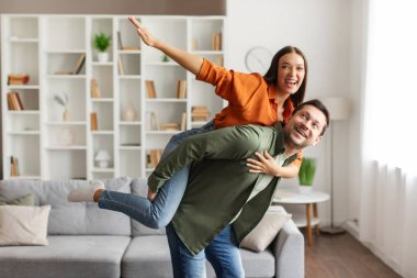Romantik Avrupalı eşler evde eğleniyor, sevgi dolu bir adam karısını sırtında taşıyor, evde birlikte vakit geçiriyorlar ve kameraya gülümsüyorlar, mekanı kopyalıyorlar.