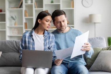 Aile bütçesini dengelemek. Eşler kağıt faturalarını gözden geçirir ve dizüstü bilgisayar kullanır, evde online finansman yönetir. Evrak işi kavramı