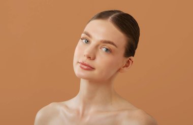 Cilt bakımı ve doğal güzellik kavramı. Parlak tenli güzel Avrupalı kadın, bej renkli stüdyo arka planında izole edilmiş poz veriyor.