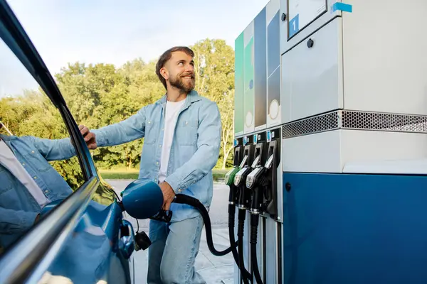 Benzin istasyonunda yakıt ikmali yapan bir adam. Benzin deposunu doldurup benzin sayacına bakıyor.