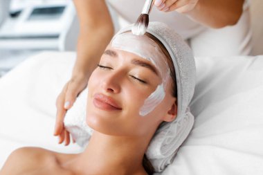 Profesyonel kozmetik uzmanı bayanların yüzüne besleyici krem sürüyor, cilt bakımını nemlendiriyor. Güzellik merkezindeki kozmetik prosedürleri