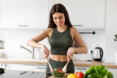 Sıska bayanın taze sebze salatası yapması kâsede malzemeleri karıştırması sağlıklı beslenme düzeninin ve besleyici yemek hazırlığının keyfini çıkarması.