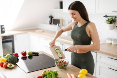 Mutlu formda bir kadın taze sebze salatası pişiriyor, mutfağın içinde zayıflamak için yemek hazırlıyor, kilo vermek için diyet yapıyor, bedava yer açıyor.
