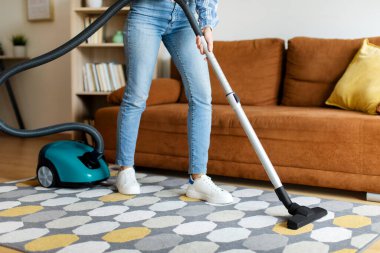 Temizlik konsepti. Oturma odasında süpürge ve halı kullanan bir kadın, ev işleri ve ev işleri yapan bir kadın.