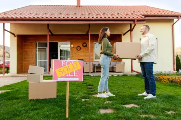 Eşler taşınma gününde yeni evlerinin önünde kutu ile duruyorlar. Ön planda, tam boy, kopyalama alanı var.
