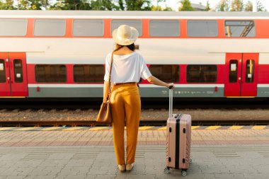 Modern iki katlı tren istasyonuna bakan turist kadının arka görüntüsü, tren istasyonunda tam uzunlukta duruyor.