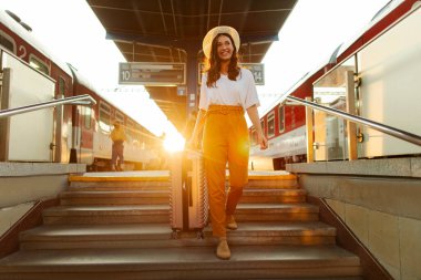 Bavullu mutlu kadın tren istasyonunda merdivenlerden iniyor. Tatil için New City 'ye geliyor.