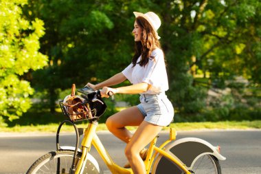 Ekolojik nakliye. Şehir parkında bisiklete binen mutlu kadın, yan görüntü. Modern şehir ulaşım kavramı
