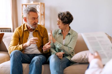 Evlilik psikoterapisi. Mutsuz emekli çift terapi seansı sırasında kavga ediyor ilişkilerde kriz yaşıyor, kanepede oturuyor.
