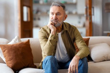 Hayal kırıklığına uğramış yaşlı bir adam koltukta tek başına oturuyor, ellerine yaslanıyor, zorluklar yaşıyor, boşanma sürecinden geçiyor.