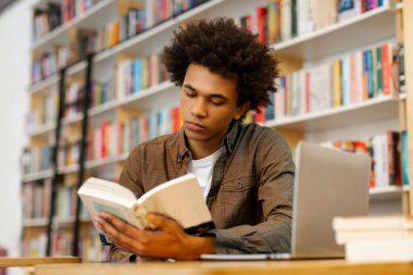 Sınav hazırlıklarına, kitap okumaya, ders ve derslerden sonra üniversite kütüphanesinde oturmaya odaklanmış Latin erkek öğrenci.