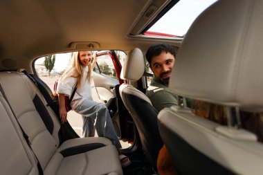 Baba kızını okuldan alıyor, kız arabada arka koltukta otururken baba sürücü koltuğunda oturuyor ve tekrar kıza dönüyor.