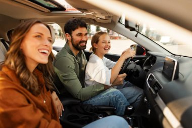 Küçük çocuğa araba sürmeyi öğreten mutlu bir adam, direksiyon tutan ve yola bakan bir kız. Baba ve kızı hafta sonları eğleniyorlar.