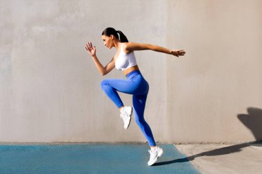 Sıska bir kadının ısınırken zıplaması, şehir dışında egzersiz yapması, uzun menzilli çekim. Spor motivasyonu kavramı