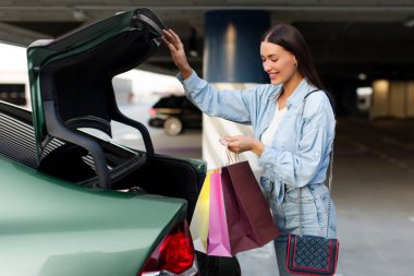 Mutlu Avrupalı kadın alışveriş torbalarını bagaja koyup alışveriş merkezinden eve gitmeye hazır hale getiriyor.