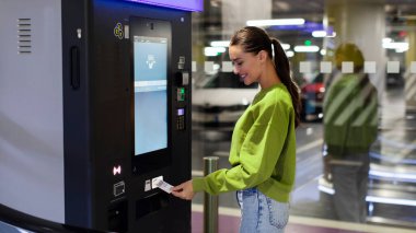 Alışveriş merkezinin yeraltı otoparkında park cezası ödeyen kadın.