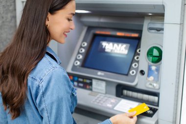 ATM kullanan, kredi kartı kullanan, karttan para çeken ve dışarıda para transferleri yapan bir kadın.