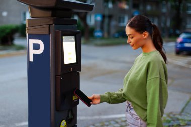 Kadın sürücü cep telefonunu NFC 'nin oradaki açık hava park yeri için kullanıyor. Temassız ödeme sistemi