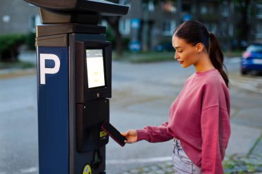 Kadın sürücü cep telefonunu NFC 'nin oradaki açık hava park yeri için kullanıyor. Temassız ödeme sistemi