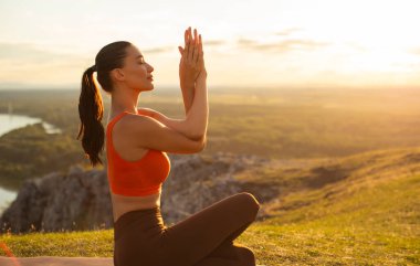 Genç sakin bir kadın doğada yoga yapıyor, gün batımında dışarıda meditasyon yapıyor, yan görüş, kopyalama alanı. Canlılık, farkındalık, zen enerjisi kavramı