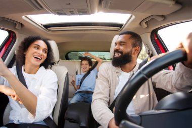 Aktif eğlence, aile gezisi. Latin aile ve oğlu araba sürerken eğleniyorlar, müzik dinliyorlar ve dans ediyorlar, gösterge panelinden çekiliyorlar.