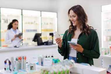 Barkod detaylarını kontrol eden mutlu kadın müşteriler, bir sürü ilaçla birlikte rafın yanındaki eczanede duruyorlar.