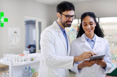 Eczanede dijital tabletle çalışan mutlu erkek ve bayan eczacılar, ücretsiz alan