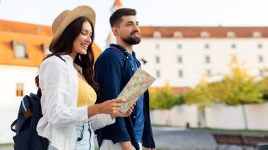 Genç mutlu çift eski şehirde yürüyor, kadın haritaya bakıyor ve şehir simgelerine giden yolları arıyor yaz gezisinin tadını çıkarırken, bedava uzay
