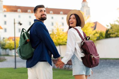 Mutlu turistler el ele tutuşup geri dönerler, şehri ve manzarayı görürler.