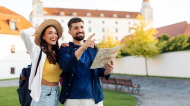 Mimariden zevk alan turist bir çift, kadın ve erkek eski şehir sokaklarında yürüyor, adam haritayı işaret ediyor ve tutuyor.