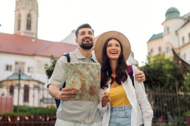 Heyecanlı bir çift şehirde haritayla yürüyor, tatili eski şehrin sokaklarını keşfederek geçiriyor, erkek kadını kucaklıyor ve hayranlıkla başka tarafa bakıyor.
