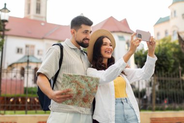 Genç bir adam ve kadın şehrin dışını yürüyerek vuruyor, birlikte seyahat ediyorlar, elinde kağıt harita tutan bir adam, cep telefonu kullanan bir kadın.