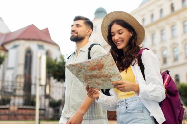 Mutlu kadın ve erkek arkadaşı şehri keşfediyor, kadın elinde tutuyor ve haritaya bakıyor, güzergah planlıyorlar.