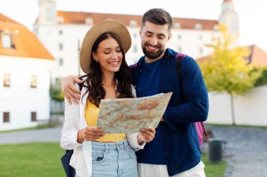 Birkaç gezgin harita kullanıyor, kasabayı gezmek için yerleri araştırıyor, adam ve kadın sokakta yürüyor ve birlikte seyahat ediyorlar.