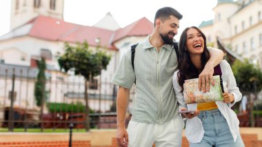 Tasasız Avrupalı gezginler yaz tatili gezileri sırasında şehirde yürürken kucaklaşıp sohbet ediyorlar.