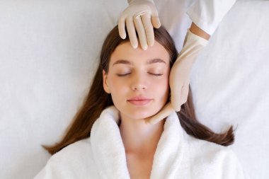 Eldivenli doktor güzel bir kadının yüzüne masaj yapıyor, eldiven takan profesyonel bir kozmetik uzmanı, güzellik salonunda çalışıyor,