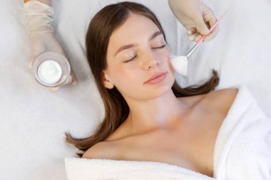 Kozmetik uzmanı, ultrasonik ve mekanik temizlik prosedüründen önce cildin soğuk hidrojenleşmesi için jel kullanıyor. Güzellik salonunda cilt bakımı gören kadın.