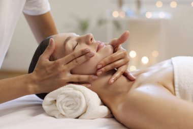 Rahatlamış kadın spa salonunda kafa masajı yaptırıyor, güzellik terapisinden zevk alıyor, kozmetoloji dolabında sağlık günü, yakın çekim, yan görüş.