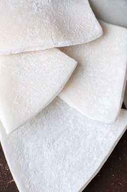 Sarı arka planda kurutulmuş hindistan cevizi dilimleri, yakın plan.