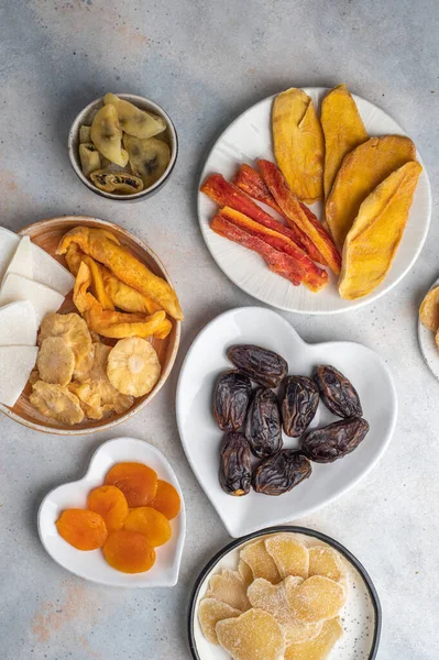 stock image Assorted exotic dried fruits on plates on a white background. Dried mango, papaya, pineapple, jackfruit, date, apricot, melon, pineapple, passion fruit, ginger. Top view