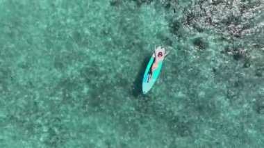 Turkuaz Maldivler 'in sularında zarif bir şekilde kürek çeken güzel bir kız, göz kamaştırıcı bir hava manzarası yakalamış.